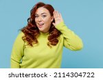 Small photo of Young curious nosy chubby overweight plus size big fat fit woman in green sweater try to hear you overhear listening intently isolated on plain blue background studio portrait People lifestyle concept