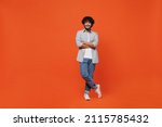 Full size body length confident happy young bearded Indian man 20s years old wears blue shirt hold hands crossed isolated on plain orange background studio portrait. People emotions lifestyle concept