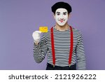 Small photo of Charismatic amazing confident happy vivid young mime man with white face mask wears striped shirt beret hold in hand credit bank card isolated on plain pastel light violet background studio portrait