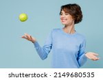 Small photo of Young smiling satisfied happy vegetarian cool woman 20s in casual sweater look camera toss up green apple isolated on plain pastel light blue background studio portrait. People lifestyle food concept.