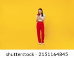 Small photo of Full size body length smiling fun young girl woman of Asian ethnicity 20s years old wears casual clothes hold in hand use mobile cell phone send sms isolated on plain yellow background studio portrait