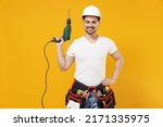 Young fun employee handyman man in protective helmet hardhat glasses holding electric drill isolated on yellow background studio. Instruments accessories renovation apartment room Repair home concept