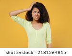 Small photo of Aggrieved disturbed displeased african american young brunette woman 20s wears green shirt look aside away hand on head isolated on yellow background studio portrait. People emotions lifestyle concept
