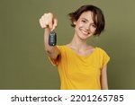 Small photo of Young satisfied smiling cheerful fun happy woman she 20s wear yellow t-shirt hold in hand give car key fob keyless system isolated on plain olive green khaki background studio People lifestyle concept