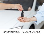 Close up woman customer buyer client female hand arm take car key from salesman chooses auto buy new white modern automobile in showroom vehicle salon dealership store motor show indoor Sales concept