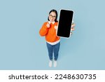 Small photo of Full body top view from above young woman of Asian ethnicity wear orange sweater glasses hold in hand use mobile cell phone with blank screen area isolated on plain pastel light blue cyan background