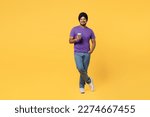 Small photo of Full body devotee Sikh Indian man ties his traditional turban dastar wear purple t-shirt hold takeaway delivery craft paper brown cup coffee to go isolated on plain yellow background studio portrait