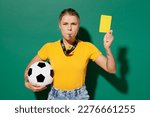 Small photo of Young sad woman fan wear yellow t-shirt cheer up support football sport team hold soccer ball yellow card propose player leave field blow whistle watch tv live stream isolated on dark green background