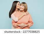 Lovely fun smiling happy caucasian elder parent mom with young adult daughter two women together wearing casual clothes hugging cuddle kiss isolated on plain blue cyan background. Family day concept