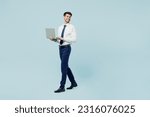 Small photo of Full body side view young employee IT business man corporate lawyer wearing classic formal shirt tie work in office hold use work on laptop pc computer isolated on plain pastel blue background studio