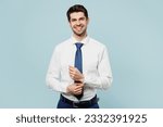 Young smiling happy successful employee business man corporate lawyer wears classic formal shirt tie work in office posing look camera isolated on plain pastel light blue background studio portrait