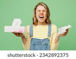 Small photo of Sick ill allergic woman has red watery eyes runny stuffy sore nose suffering from allergy trigger symptoms hay fever holding paper napkin handkerchief sneeze isolated on plain green background studio