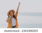 Young excited happy satisfied traveler tourist woman 20s in straw hat shirt summer casual clothes earphones listen to music outdoors on sea beach background People vacation lifestyle journey concept.