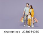 Small photo of Full body young parents mom dad with daughter girl 6 years old wearing yellow casual clothes hold shopping package bags point aside isolated on plain purple background Black Friday sale day concept