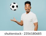 Small photo of Side view young happy man fan wear basic t-shirt look camera cheer up support football sport team hold in hand toss up soccer ball watch tv live stream isolated on plain pastel blue color background