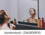 Caucasian nice young woman 20s in bra use jade face roller with natural quartz stones do massage reflected in mirror in bathroom do morning routine Skin care healthcare cosmetic procedures concept.