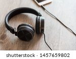 Black headphones and smartphone on wooden background.