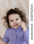 Small photo of Little kid girl after accident laying down with adhesive palter on face.