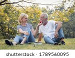 Couples senior give apples to each other together happily in the park. Concept of an elderly lover. Senior give apple to each other with smiling faces and happy.