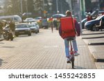 Small photo of Young boy on bicycle delivering food in boxes with red thermal bag. Pizza delivery cyclist carries isothermal backpack. Food delivery in any weather around the clock. Food delivery or takeout