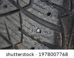 Small photo of Missing spikes. Worn tire tread, winter studded tire - wheel service. Old tires cause road accidents. Old winter studded tire close up. Used snow tire with missing steal studs closeup.