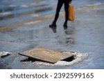 Small photo of Hole on footpath. Broken manhole, pothole in paving slabs, damaged sidewalk, shifted manhole frame. Damaged and open sewer hatch. Accident with sewer hatch in city. Pedestrian legs on background