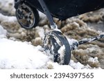 Small photo of Baby stroller wheels stuck in wet snow in winter season. Baby carriage stand on snowy road during heavy snowfall in the city, walking problem in winter season. Wheels of baby carriage stuck on sleet