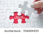 Close up of girl's hand placing the last jigsaw puzzle piece with motivation word : New Life Chapter One