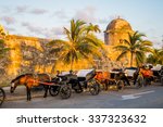 Horse drawn touristic carriages waiting alongside the fortified walls of the historic Spanish colonial city of Cartagena de Indias in Colombia