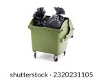 A green dust bin full of rubbish sacks