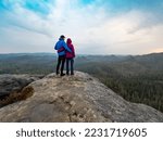 Hikers couple on the mountain edge looking over valley. Woman and man on trail on mountains paths. Love,  man and woman holding hips. Majestic mountains as a background. 
