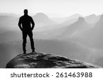 Tall hiker stand on peak of sandstone rock in rock empires park and watching over misty and foggy morning valley to Sun. Beautiful moment miracle of nature.Men silhouette stand.Tall shadow.Cold sunset
