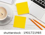 Office desk with yellow stickers, coffee and laptop. Remote office and work from home concept. Top view flat lay with copy space