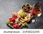 Small photo of Antipasto board with prosciutto, salami, crackers, cheese, nuts, olives and rose wine. With copy space