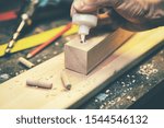 Small photo of joinery - joiner put the glue into a drilled hole for wooden dowel joint