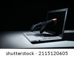 internet fraud and cyber attack concept. thief hand out of laptop screen