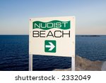 A sign indicating the direction of a nudist beach with the Adriatic Sea in the backgroung