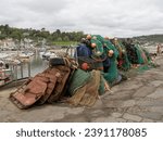 Small photo of LYME REGIS, DORSET, UK - MAY 7 2023: Fishing equipment on the Cobb with boats and harbour behind.