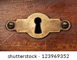 Vintage copper keyhole decorative element on weathered wooden surface