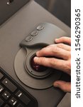 Small photo of Industrial control panel made of gray metal with operators hand on a trackball, close up photo with soft selective focus