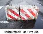 Concrete road block with warning red and white diagonal striped pattern