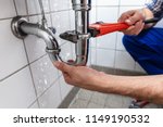 Male Plumber's Hand Repairing Sink Pipe Leakage With Adjustable Wrench