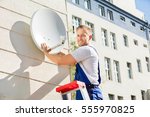 Young Man Fitting TV Satellite Dish To Wall