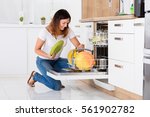 Happy Young Woman Arranging Plates In Dishwasher At Home