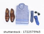 Stack of stylish ,blue striped shirts isolated with brown leather shoes ,tie ,sunglasses on white background 


