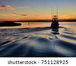 A sport fishing boat heading out of Wanchese harbor of the Outer Banks at dawn for a day of off-shore fishing.