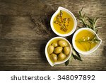 Olive oil with fresh herbs on wooden background.