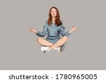 Small photo of Hovering in air. Calm peaceful relaxed girl ruffle dress levitating with mudra gesture hands up, closed eyes, meditating sitting in yoga position. indoor studio shot isolated on gray background