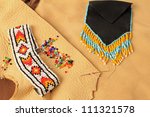 Small photo of Beaded bracelet and wampum purse on assorted leather scraps in still life setting of Native American Art.