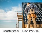 Roofer Contractor Worker on a Scaffolding. New House Construction. Roofing Job.